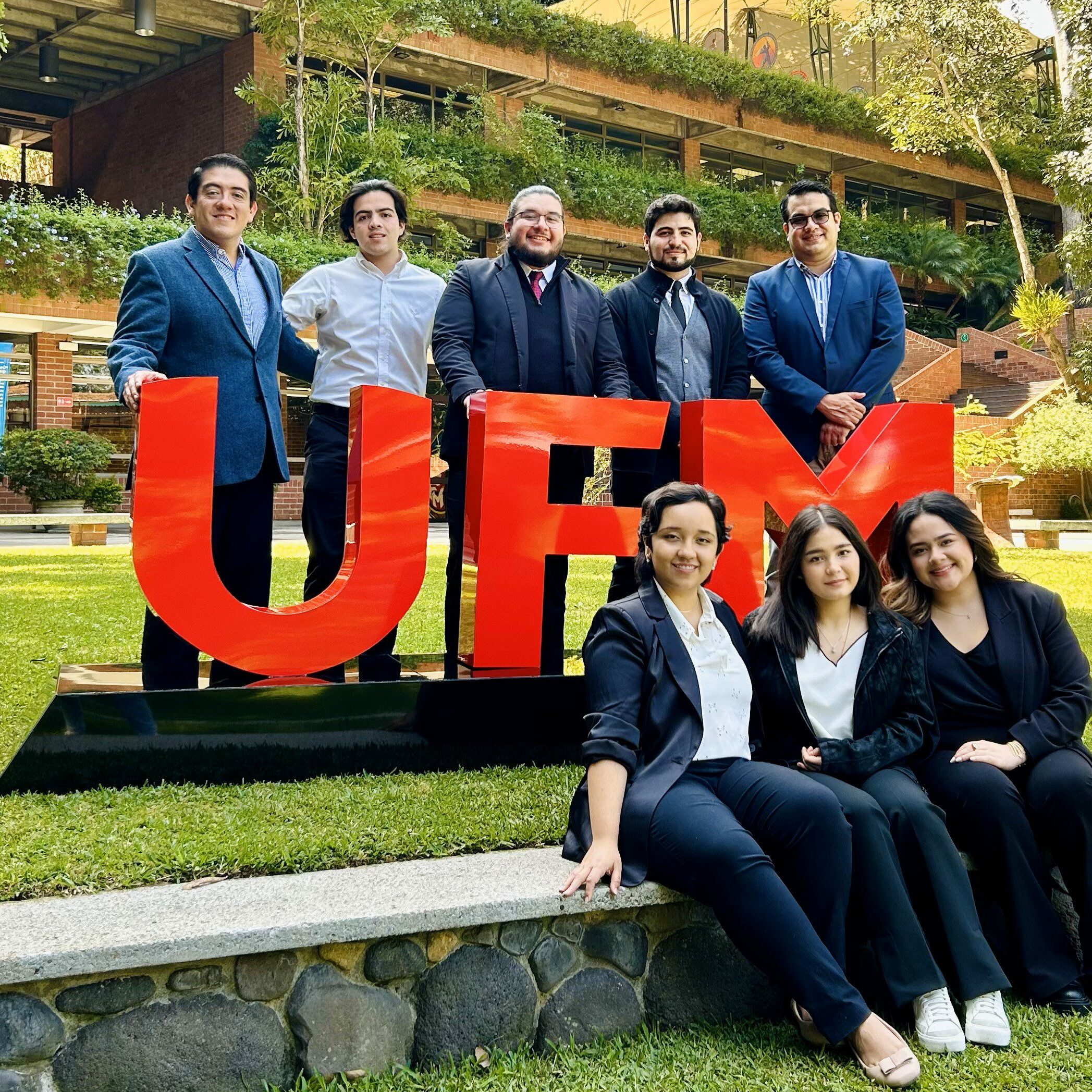 Estudiantes de CPA en finanzas con letras grandes de "UFM" en el jardín principal